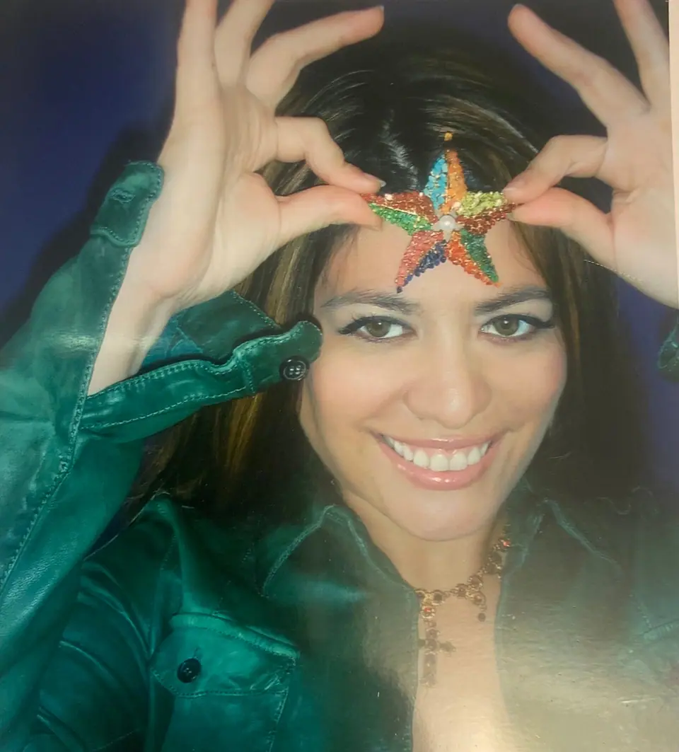Veronica Grey smiling and holding a jeweled Swoboda sea-star brooch to her forehead
